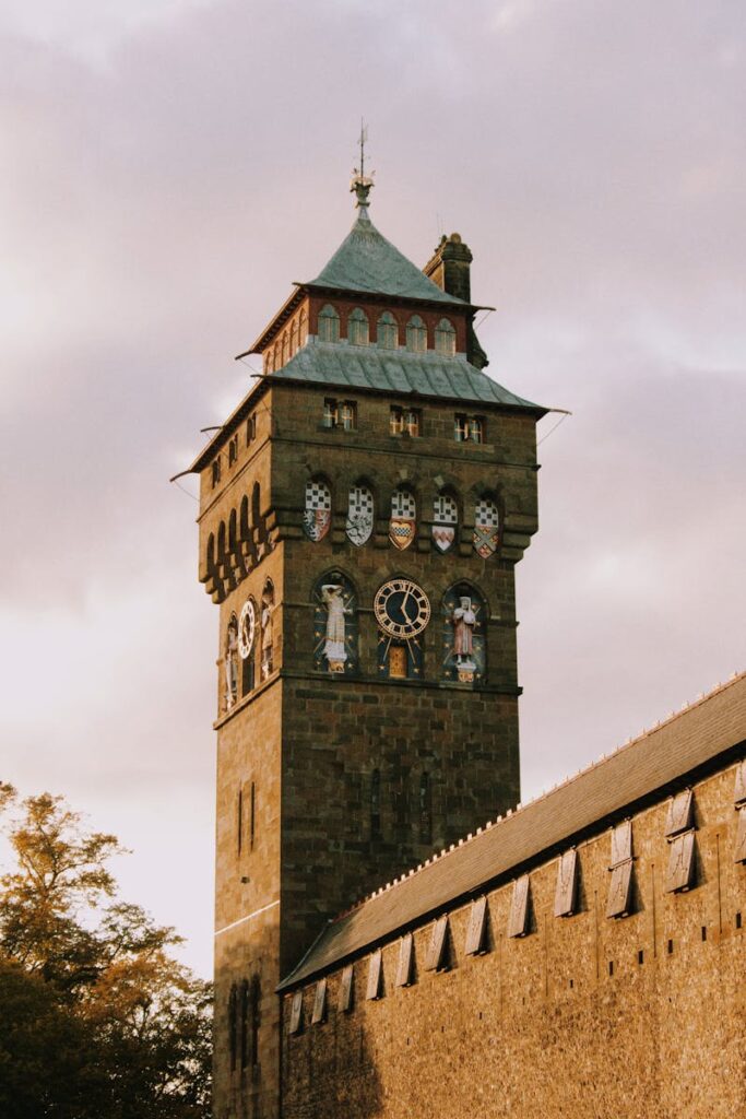 The historic clock tower of Cardiff Castle in Wales, glowing at sunrise.