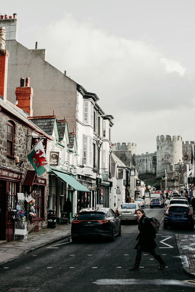 A vibrant scene of a pedestrian crossing in Conwy, Wales, with the iconic Conwy Castle in the background.